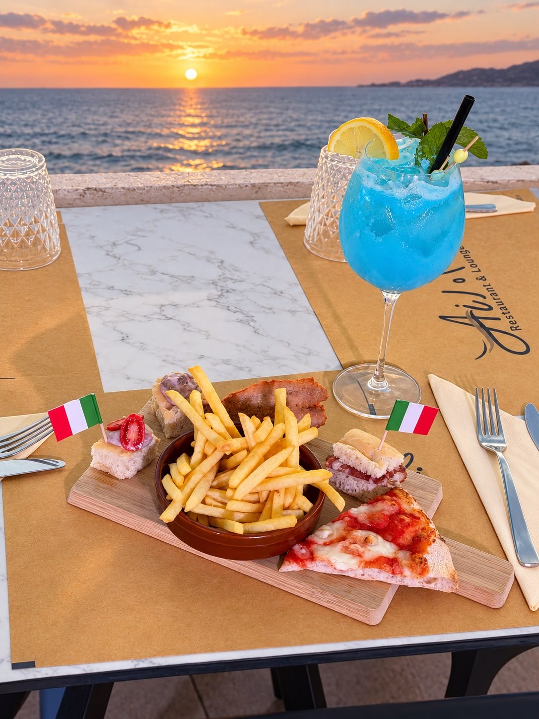Cocktail e stuzzichini Ai Medi con vista sul mare al tramonto