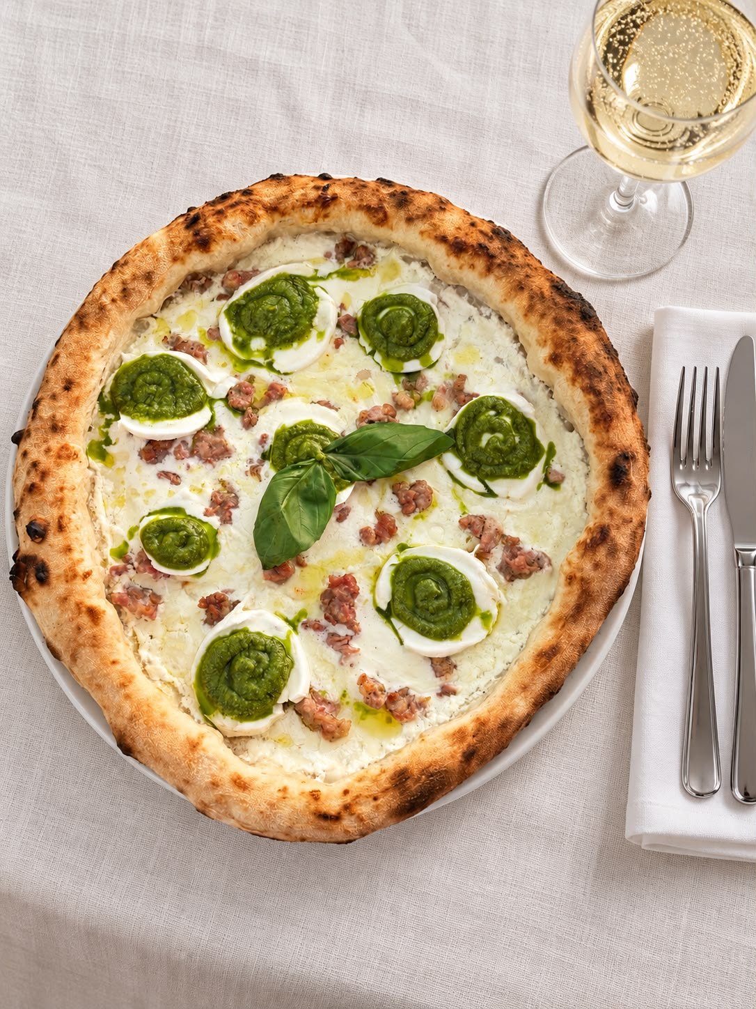 Dettaglio dall’alto di una pizza Ai Medi servita con un calice di vino